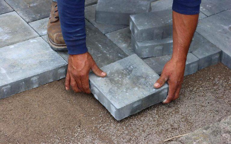man_laying_a_stone_paver_while_building_patio_close_up_800x500