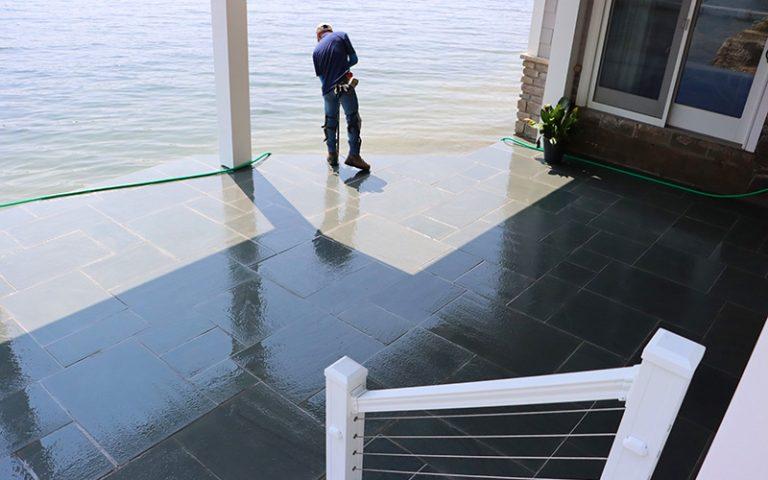 Smooth flat stone patio by lake being built finishing touches