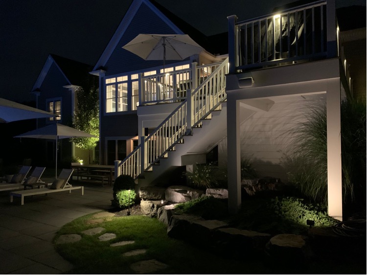 Patio with soft lighting along stairs, deck, and landscape, showcasing effective landscape lighting ideas.