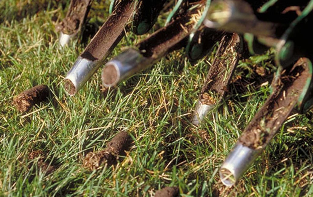 fall lawn care close-up of lawn aeration machine creating soil plugs